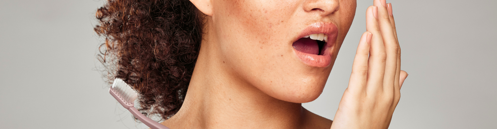 Woman blowing her breath into her hand.